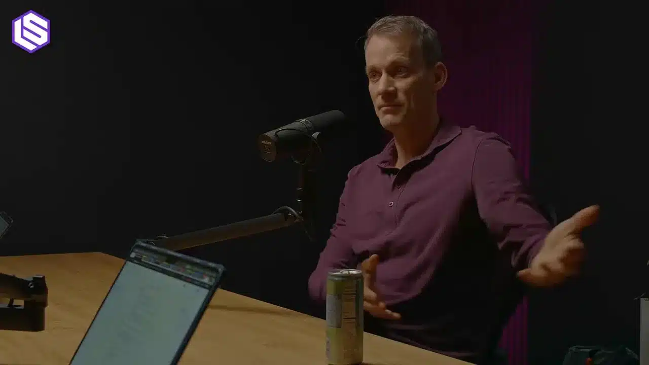 Jeff Dean über Google's Ranking Prozess 4 Jeff Dean sitzt am Tisch, blickt zur Seite und gestikuliert mit ausgestreckter Hand; Mikrofon, Laptop und Getränkedose sichtbar.