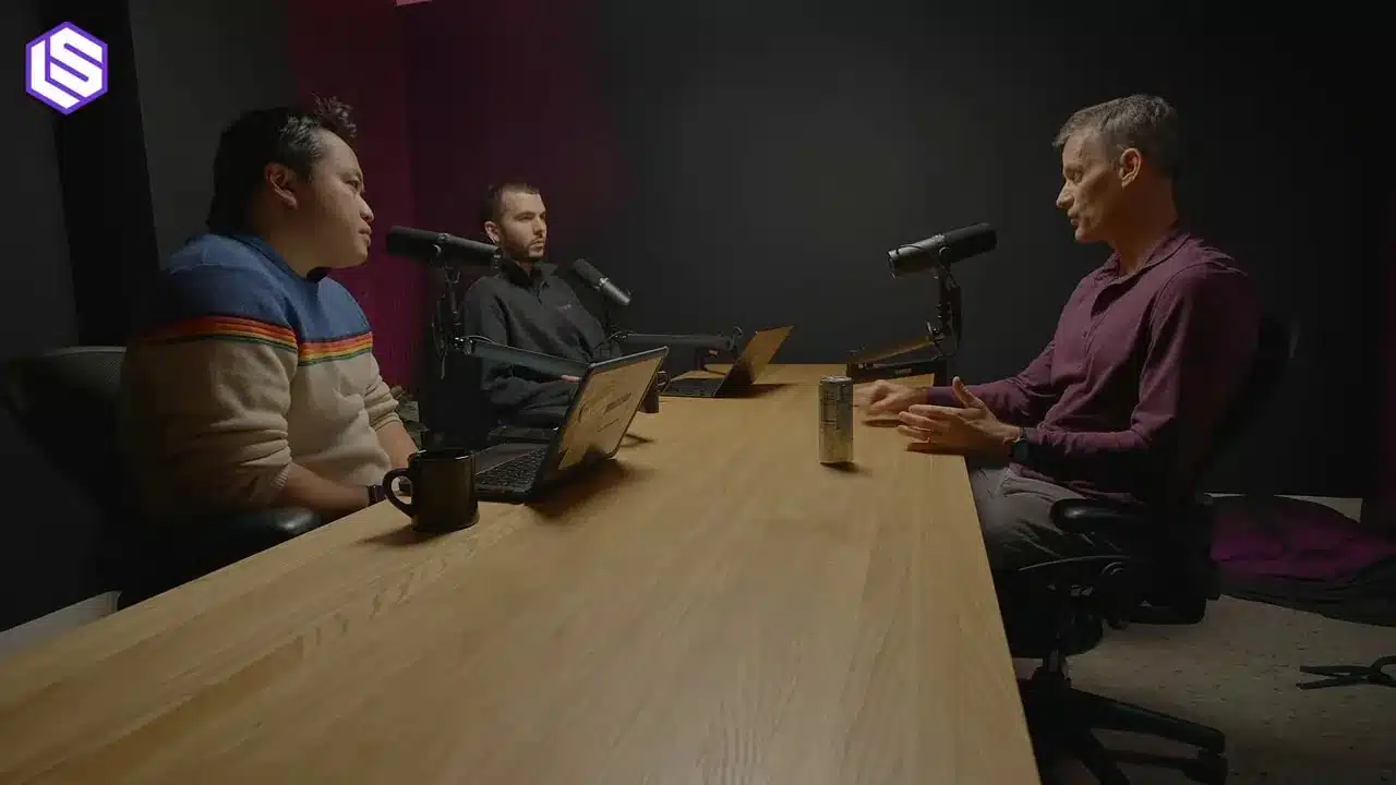 Jeff Dean über Google's Ranking Prozess 8 Weite Studioaufnahme: drei Gesprächsteilnehmer an einem Holztisch; Mikrofone, Laptops und ein Getränk auf dem Tisch sind gut sichtbar.